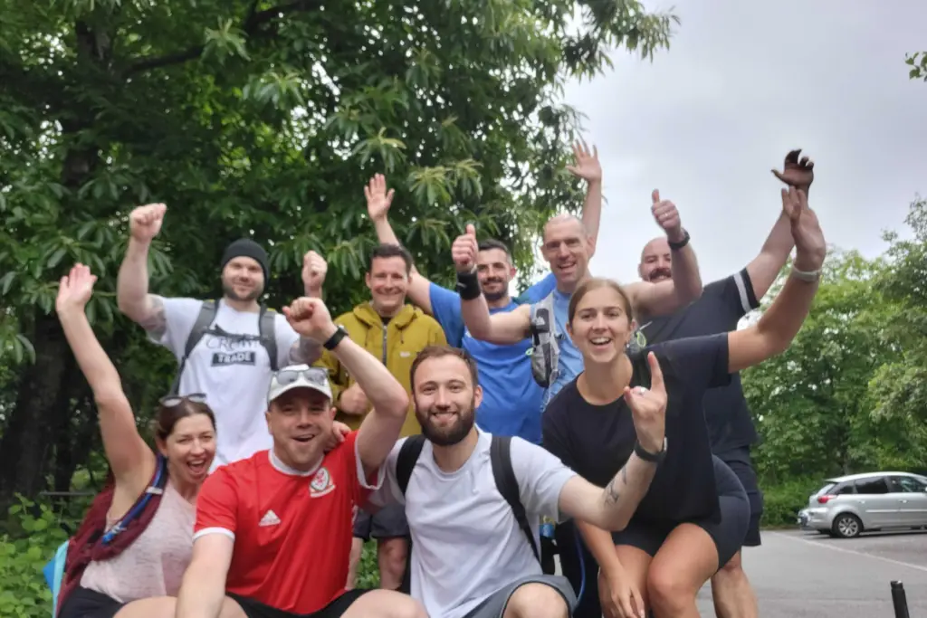 Group of people celebrating after completing a large charity walk, all in hiking clothing.