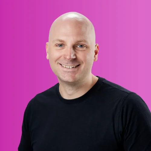 Image of Male, Adrian Hjertstedt, Chief Technology Officer. Male in black T-shirt, smiling at camera against pink gradient background.